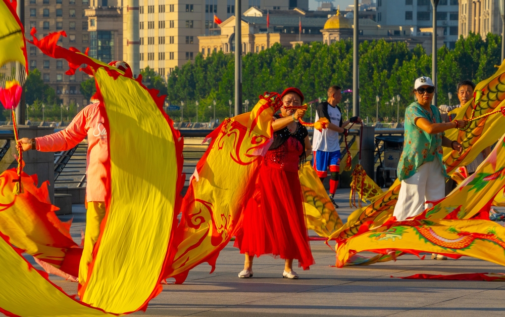 Dansatoare cu eșarfe roșii și galbene într-o piață