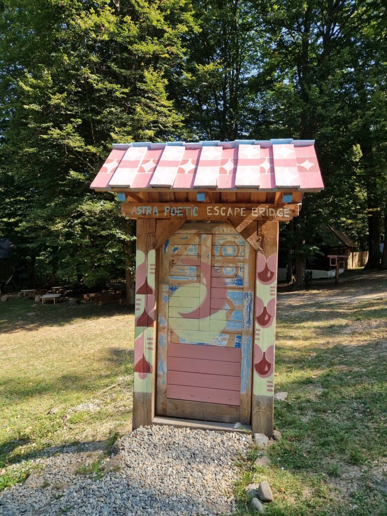 Dulăpior pictat cu acoperiș roșu, instalat lângă o alee