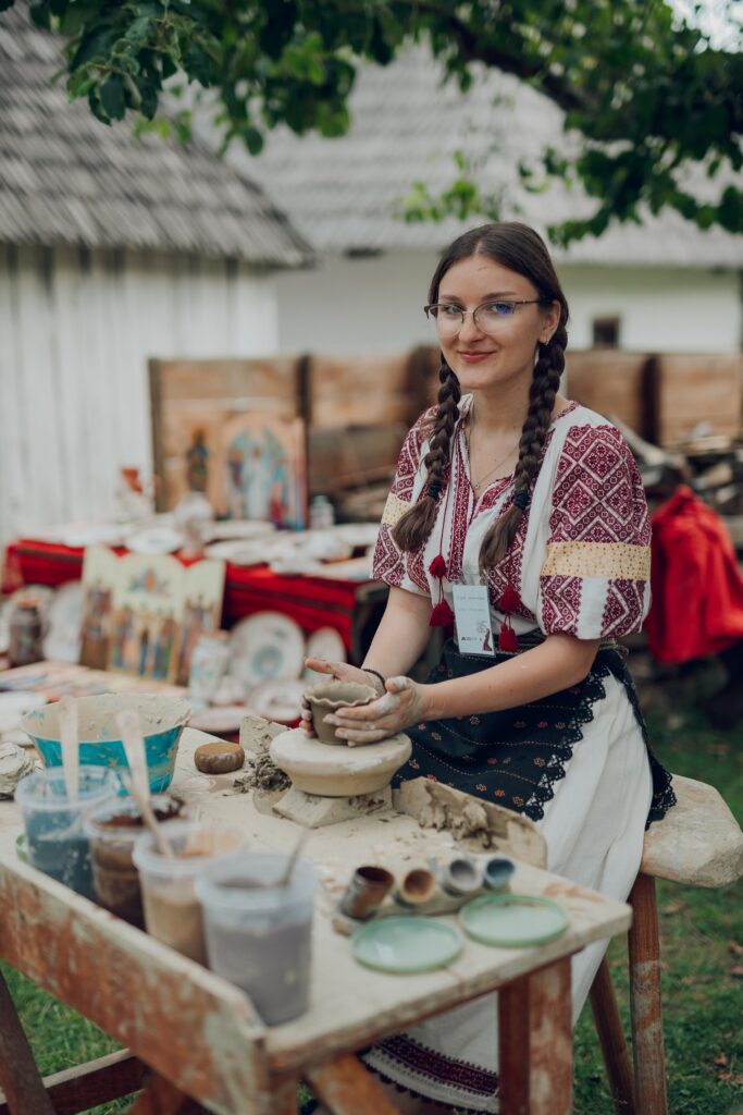 Tânără în cămașă brodată lângă o masă cu vase