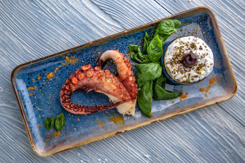 Tentacul de caracatiță pe un platou dreptunghiular, alături de sos