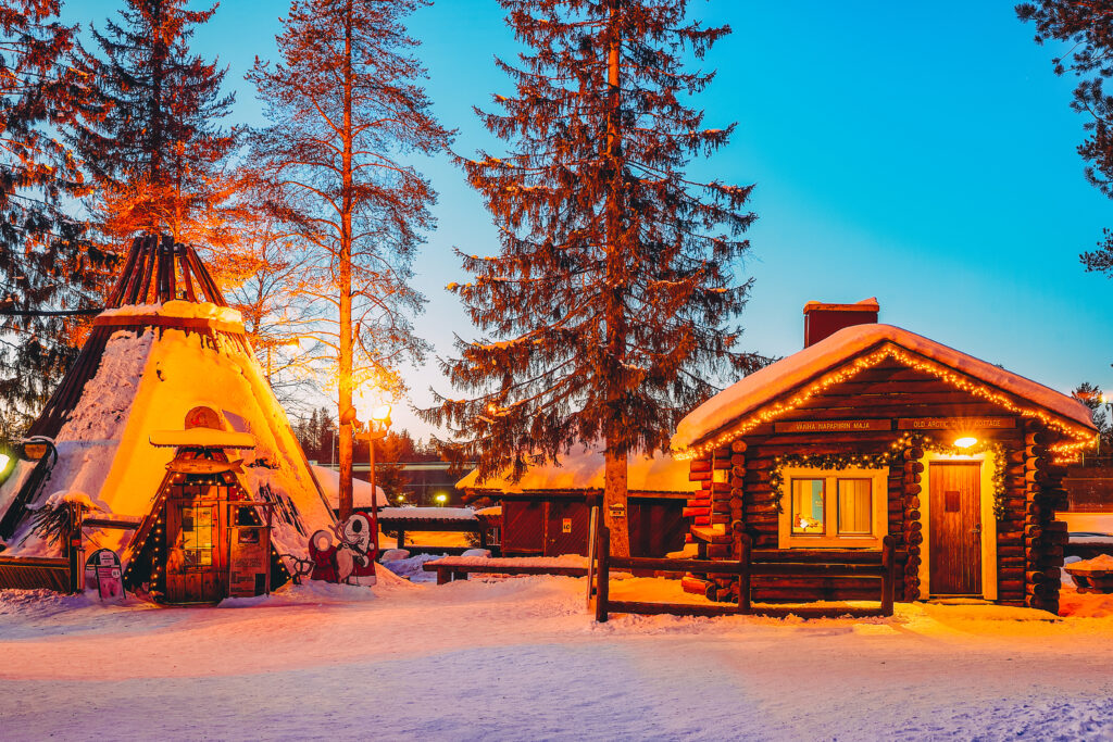 Cabane iluminate seara, printre brazi acoperiți de zăpadă