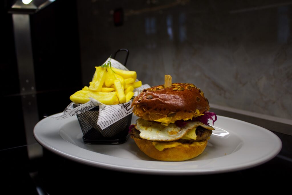 Burger și cartofi prăjiți pe o farfurie albă