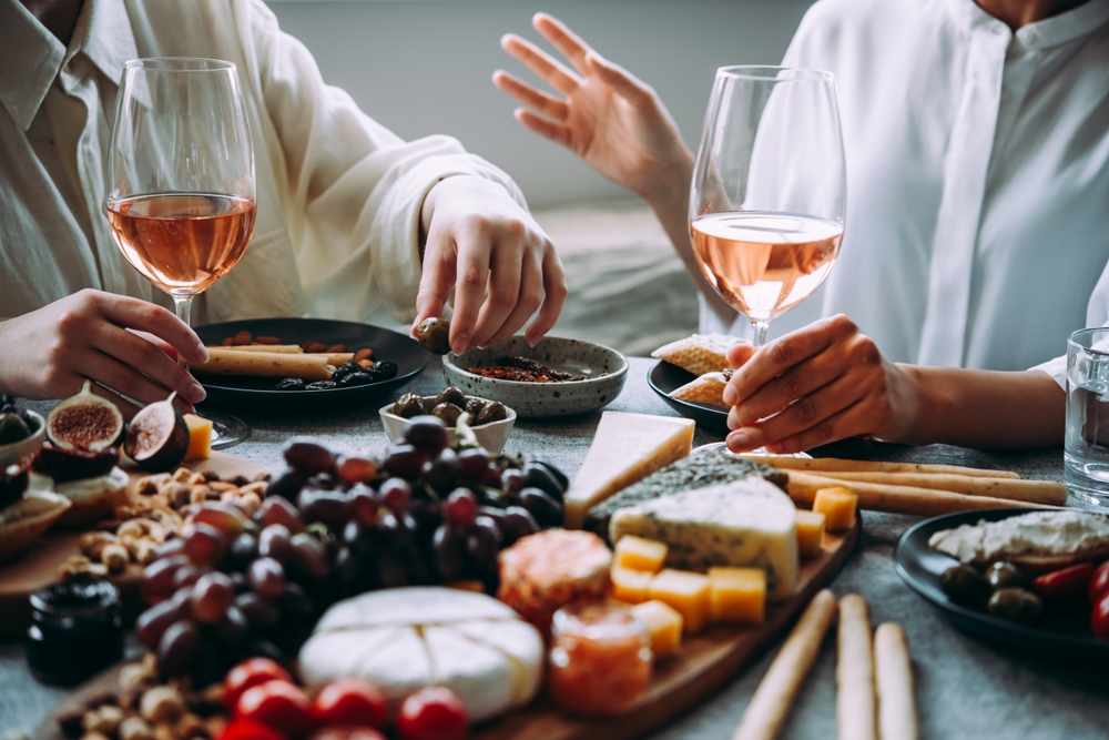 Persoane la masă cu vin, struguri și aperitive