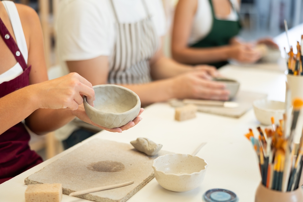 Persoane modelând lut la un atelier de ceramică