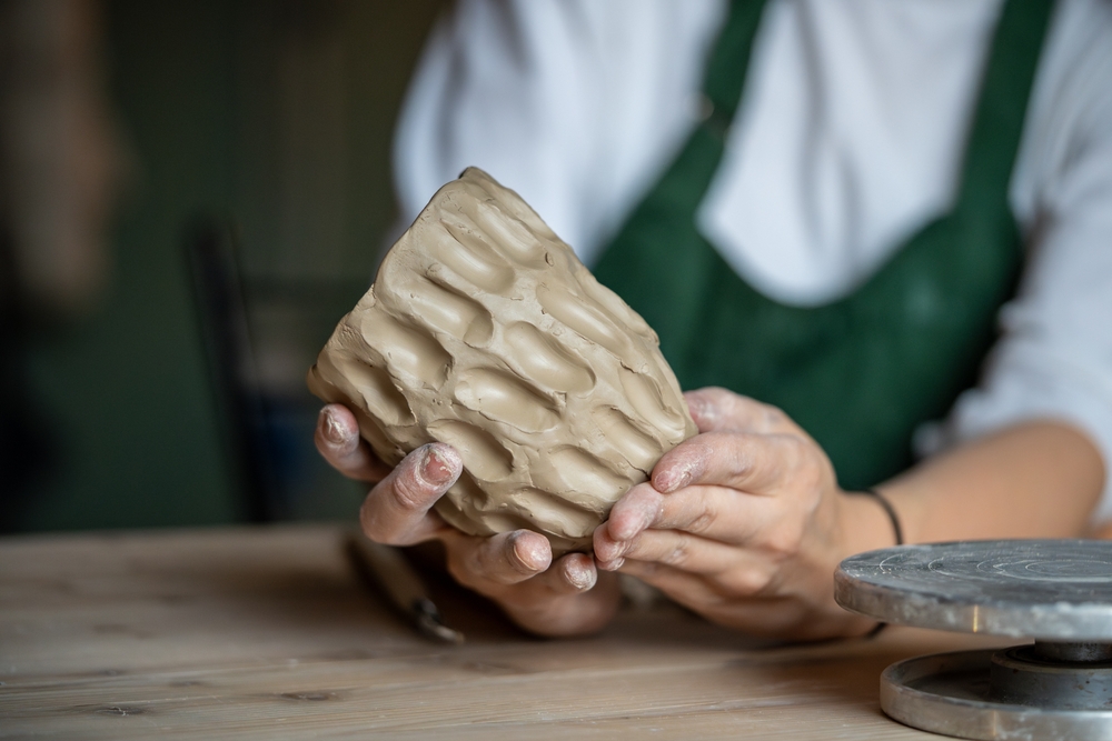 Mâini lucrând o piesă de lut cu relief