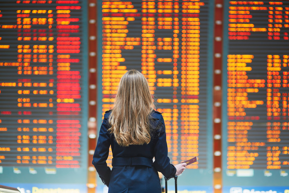 Călătoare privind panourile cu plecări și sosiri din aeroport