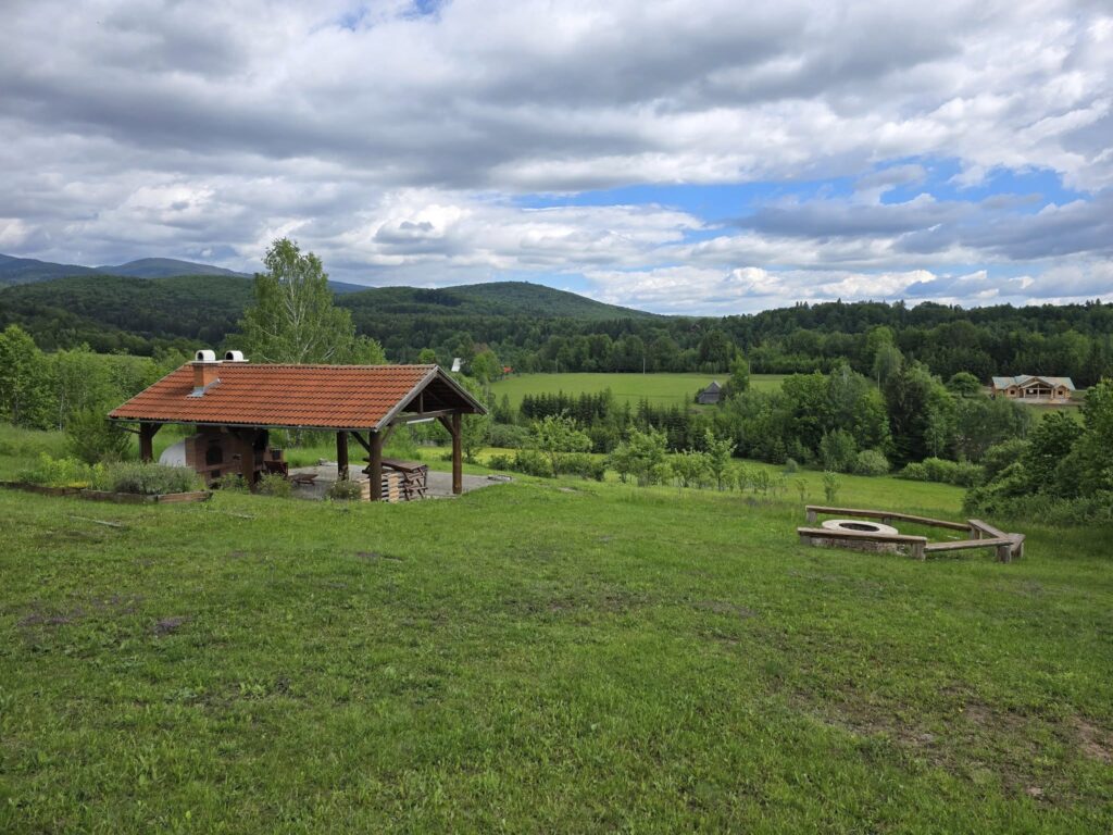 Pajiște largă cu pavilion din lemn și dealuri