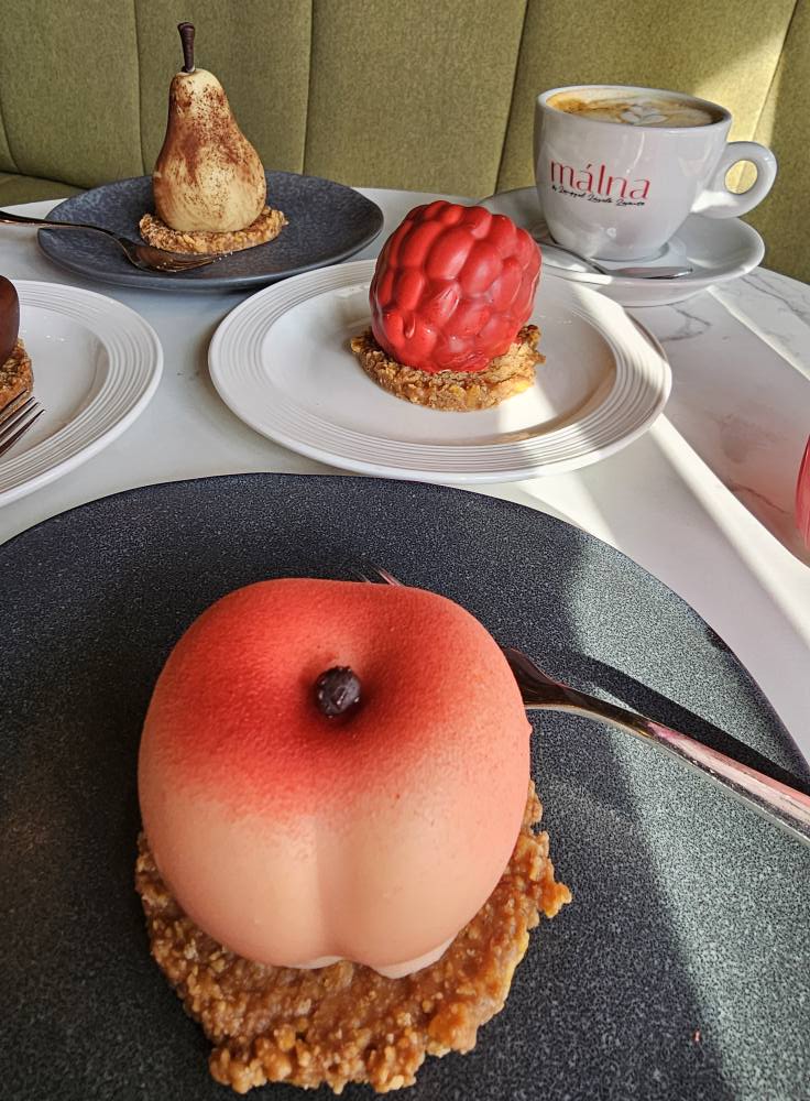 Desert rotund cu glazură roz, pe o farfurie neagră
