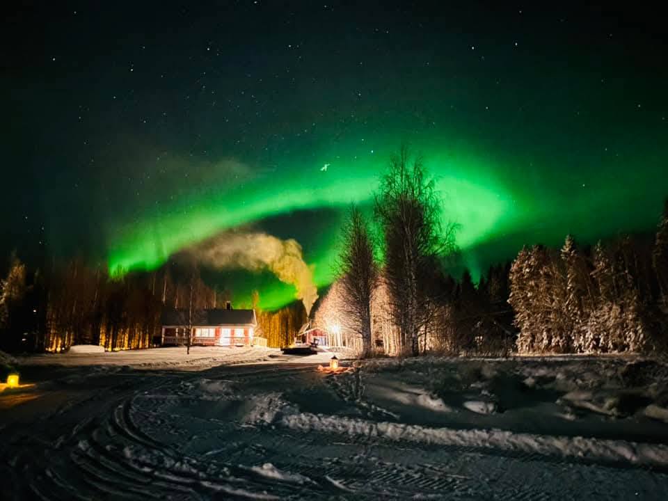 Auroră verde deasupra unui cort iluminat noaptea