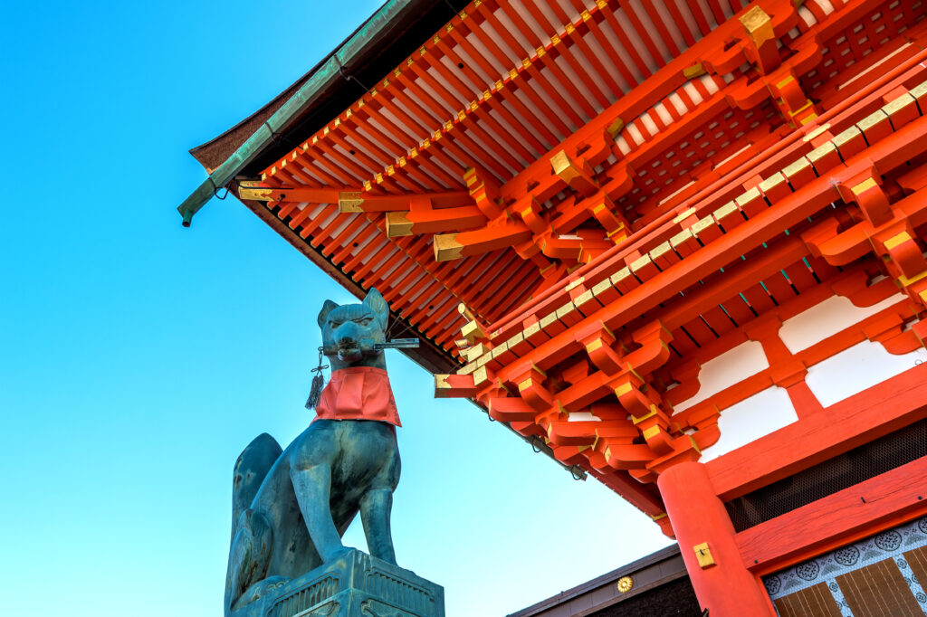 Acoperiș tradițional japonez roșu și sculptură, văzute de jos
