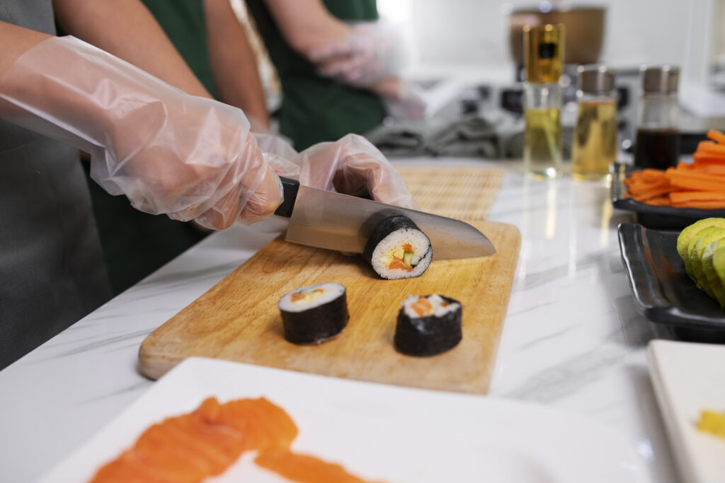 Persoană tăind rulouri de sushi pe un tocător