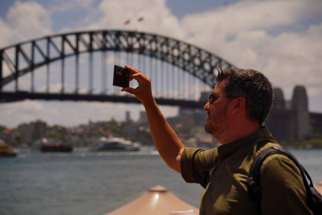 Bărbat fotografiind podul din Sydney de pe apă