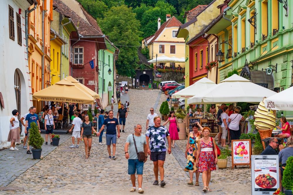 Vizitatori pe o stradă cu clădiri colorate și tarabe