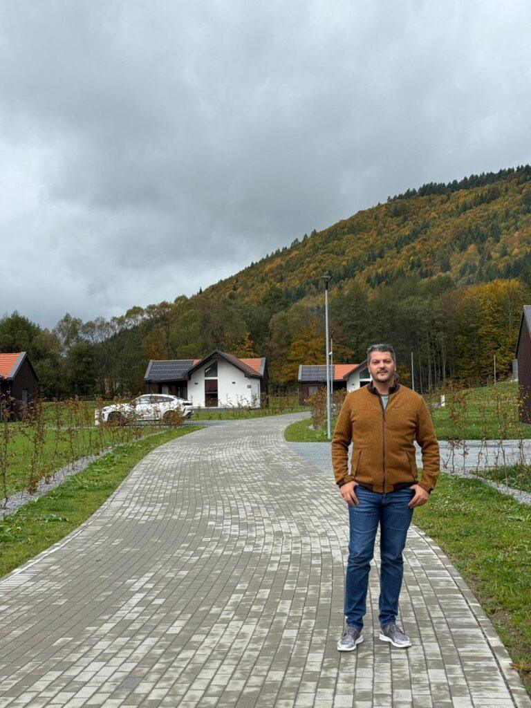 Persoană pe o alee lângă cabane și pădure