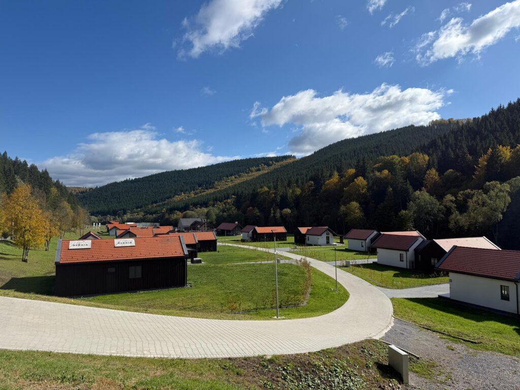 Cabane și pajiște verde, cu dealuri în fundal
