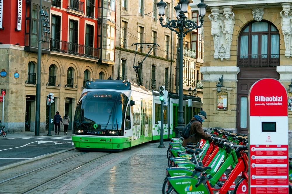 Tramvai verde pe o stradă cu biciclete și clădiri