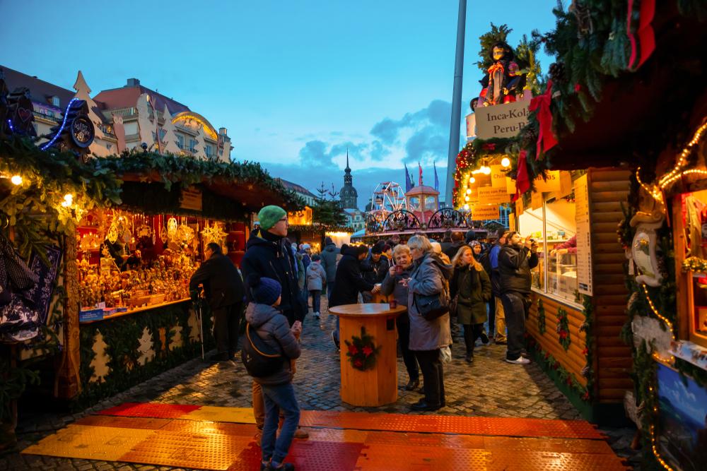 Vizitatori între standuri festive, sub cerul de seară