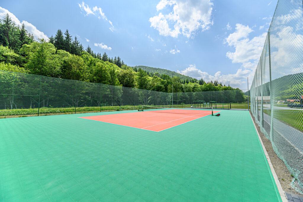 Teren sportiv verde și roșu, împrejmuit cu plasă