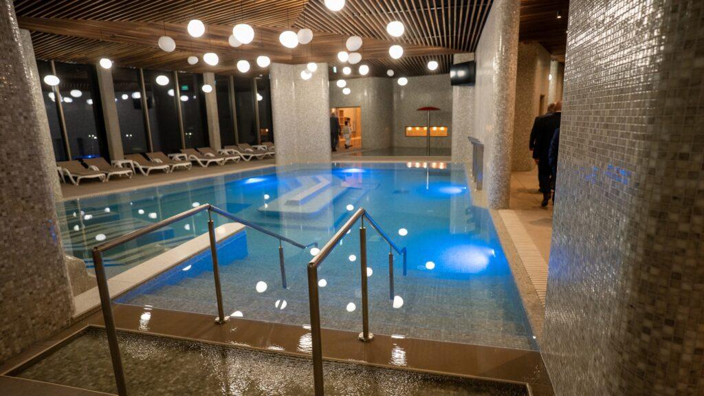 Piscină interioară cu balustradă metalică și șezlonguri