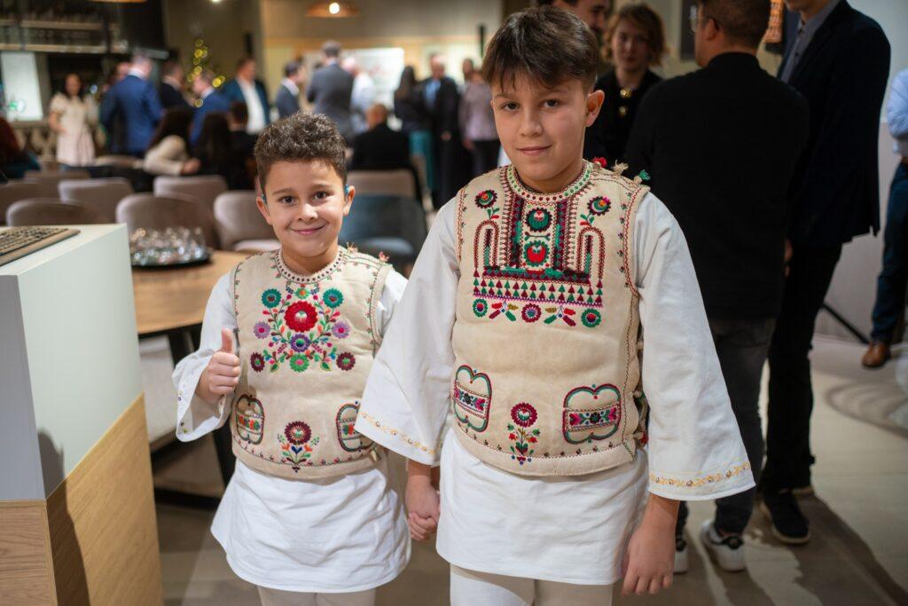 Doi copii purtând cămăși albe cu broderii colorate