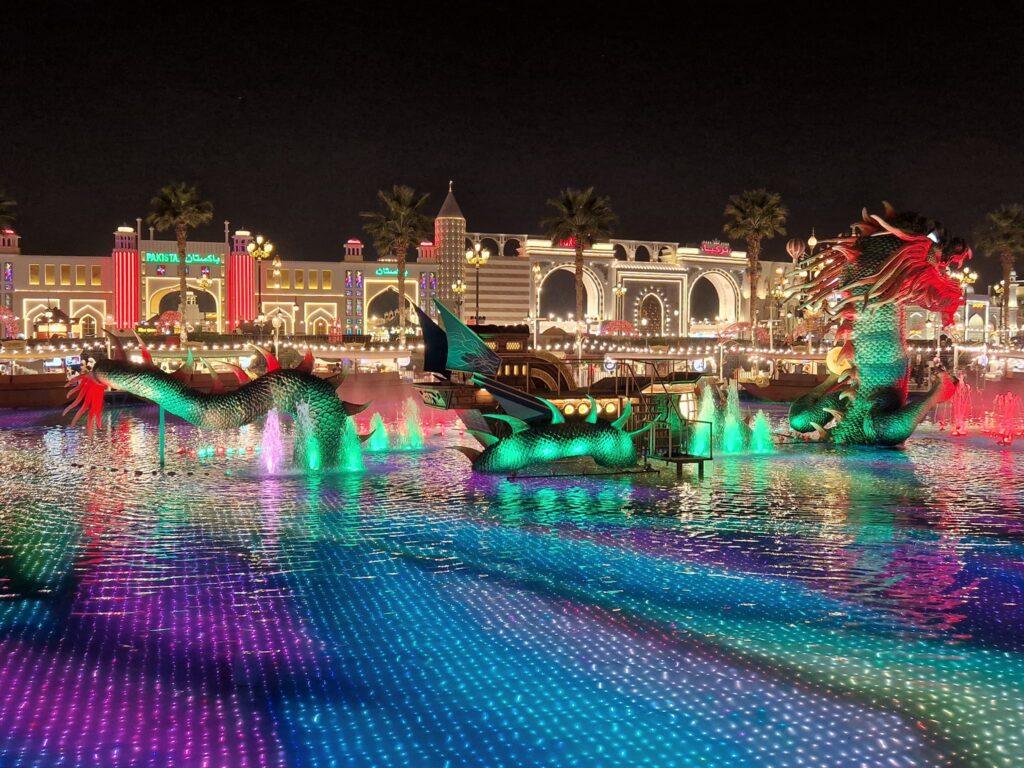 Pavilioane iluminate colorat, reflectate în apa unui canal