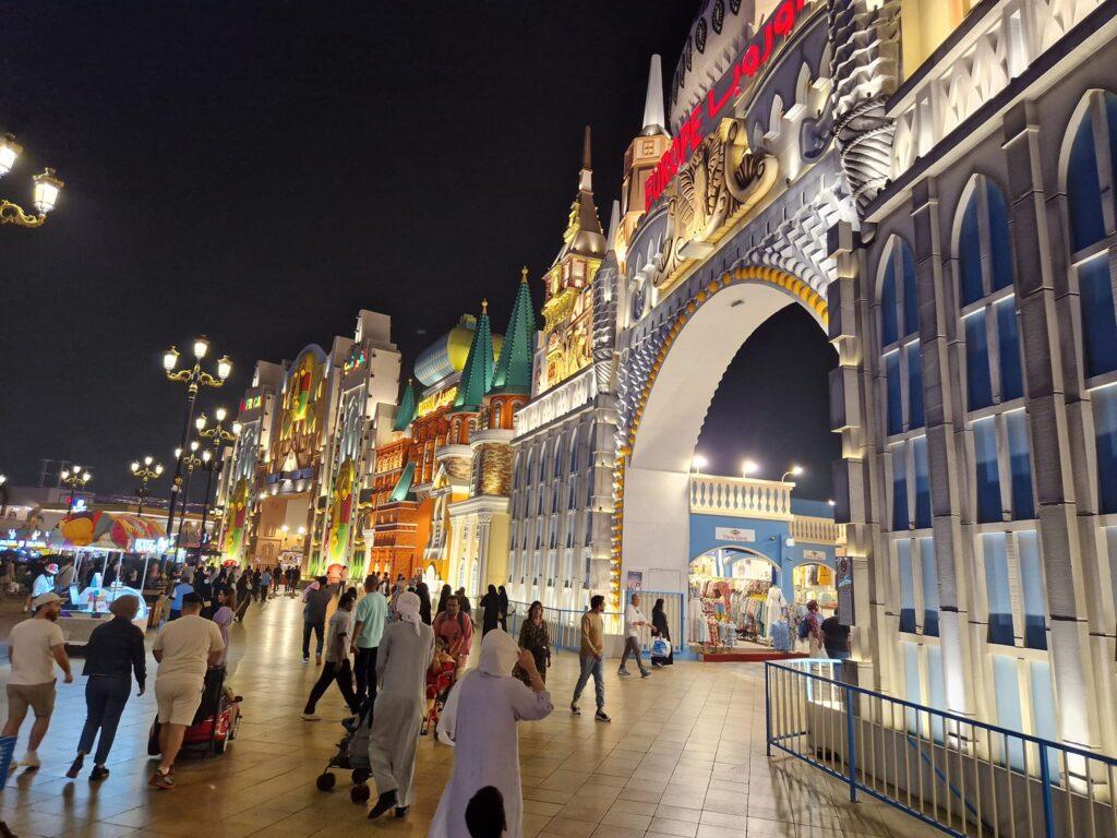 Vizitatori printre pavilioane și decorațiuni luminoase, seara