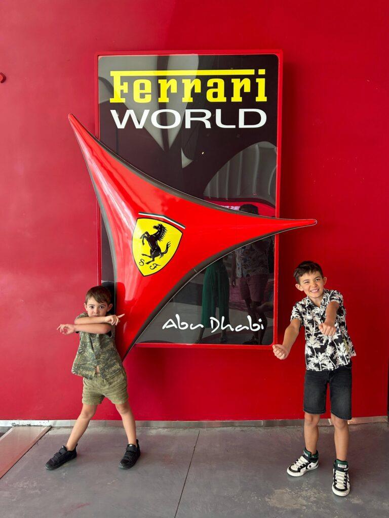 Copii lângă un panou Ferrari World roșu