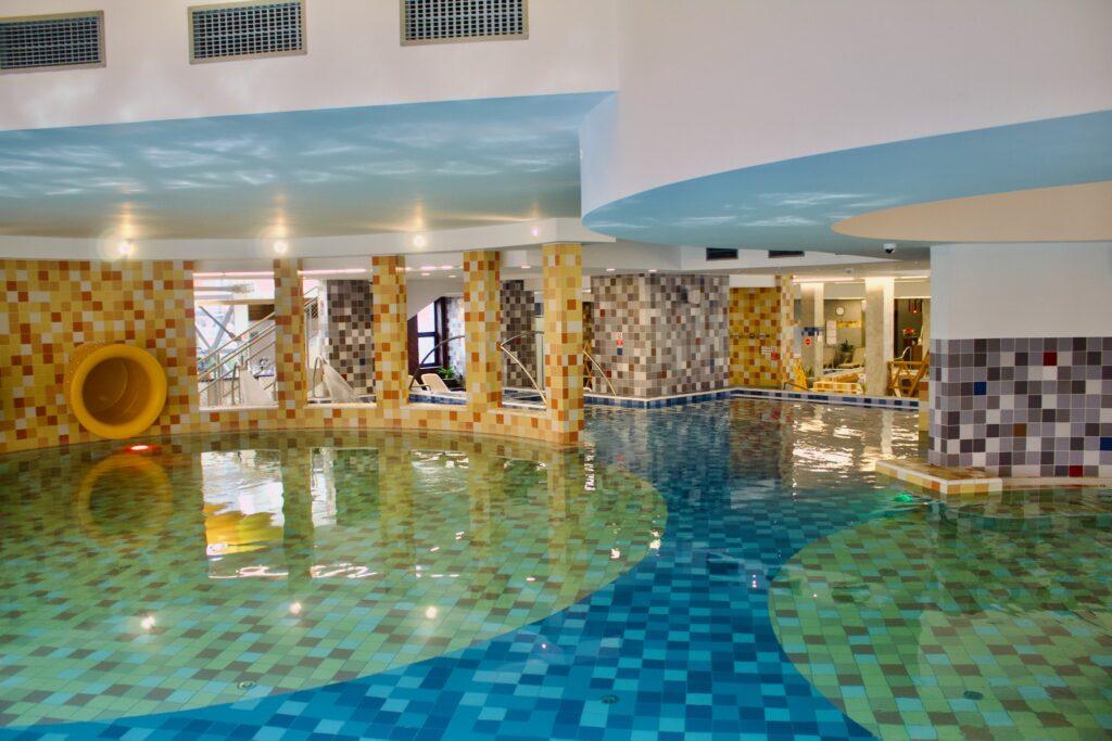 Piscină interioară cu apă verde-albastră și arcade