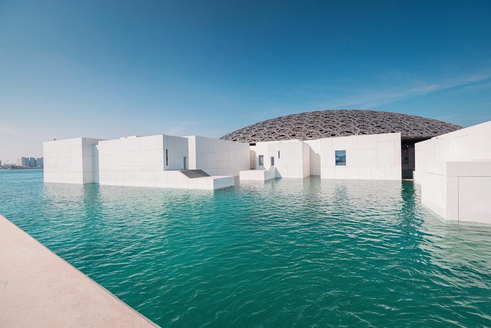 Clădirile albe ale muzeului Louvre Abu Dhabi, lângă apă