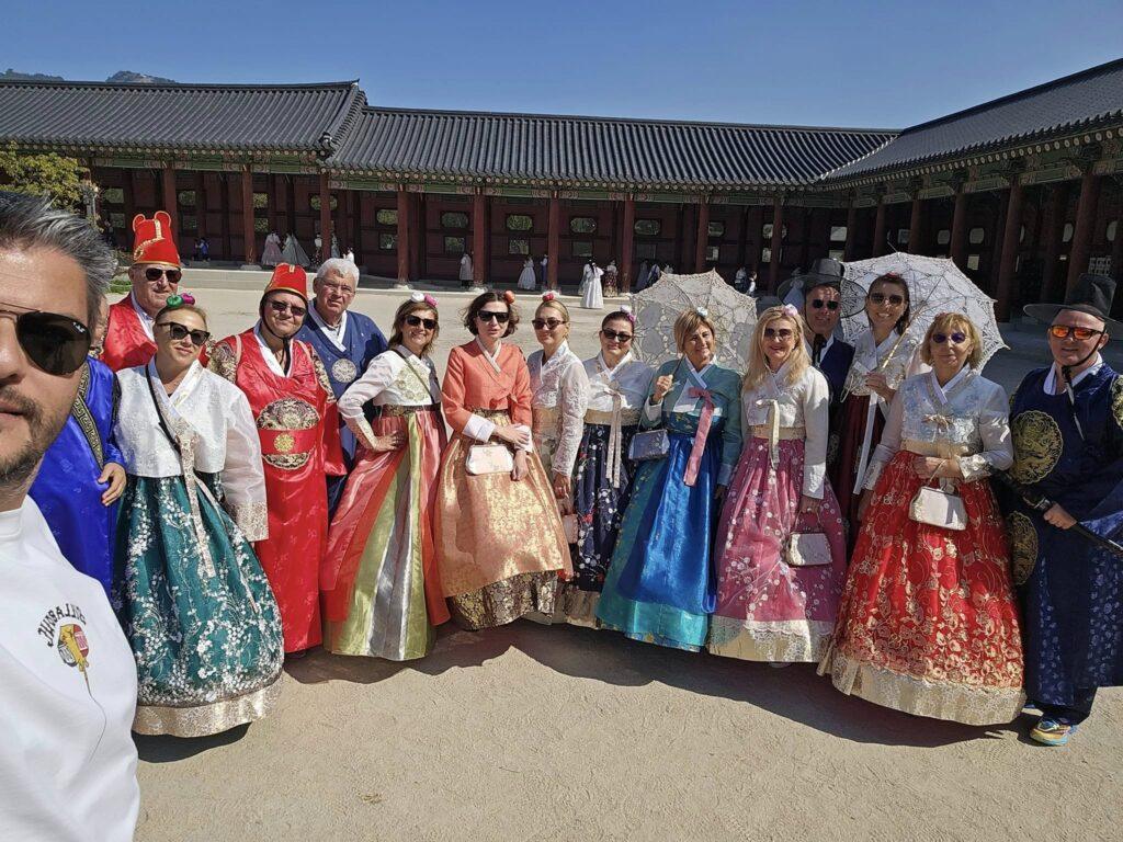 Grup de vizitatori în hanbok, lângă un zid