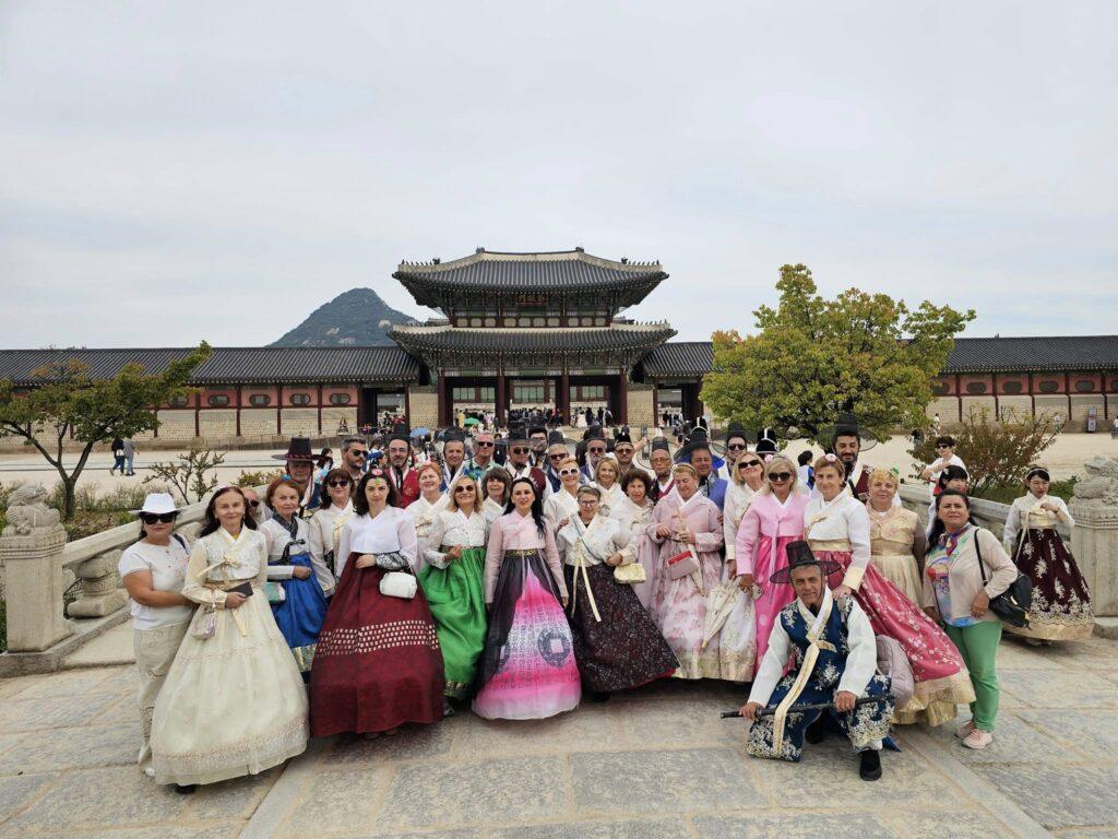 Grup de vizitatori în hanbok, în curtea unui palat
