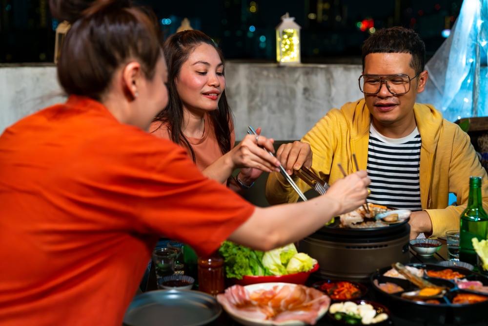Persoane servind preparate la o masă cu grătar
