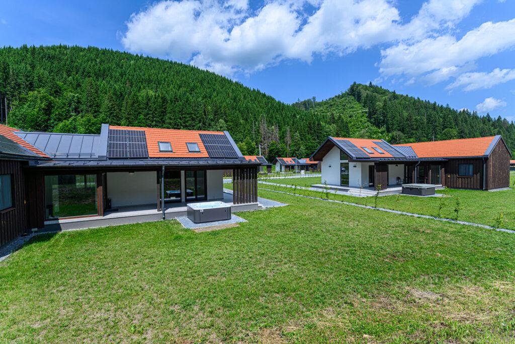 Cabane pe o pajiște, lângă dealuri împădurite