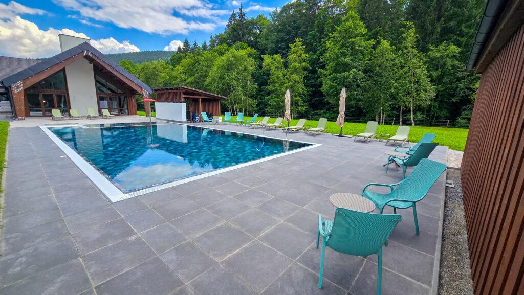 Piscină și scaune exterioare, lângă o clădire