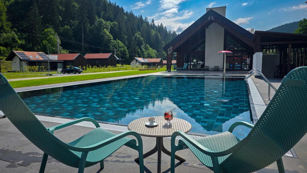 Scaune și masă pe terasă, lângă piscină