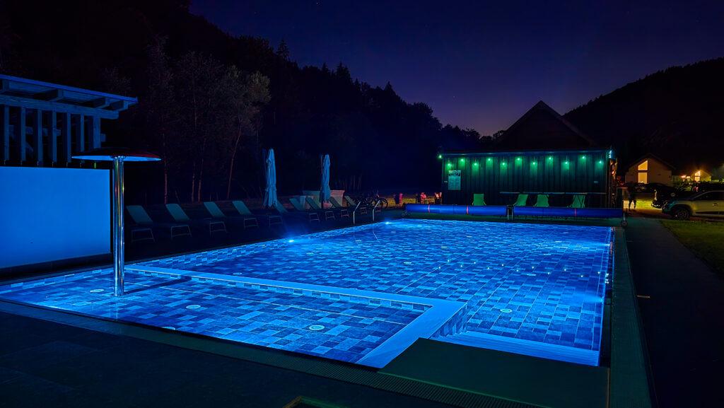 Piscină luminată albastru, într-o grădină noaptea