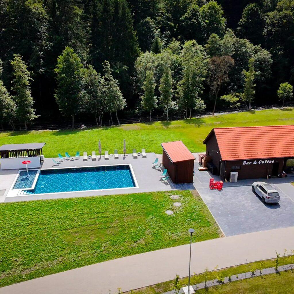 Piscină și cabane, lângă pădure, văzute de sus