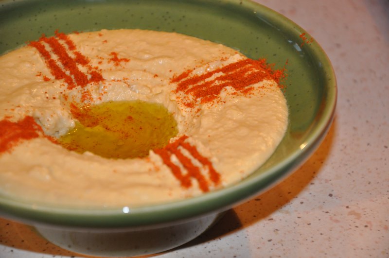 Humus cu ulei de măsline și boia într-un bol verde