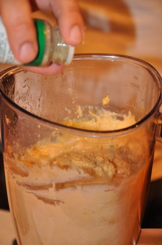Condiment presărat dintr-un recipient peste pasta din blender